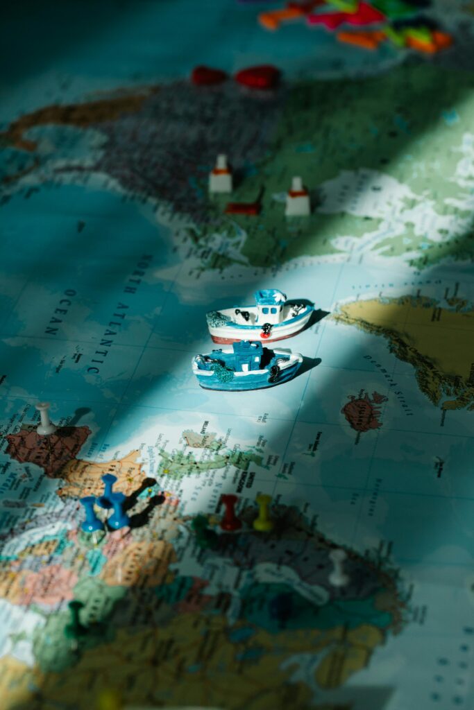 Close-up of toy boats and figurines on a world map, highlighted by a sunbeam.